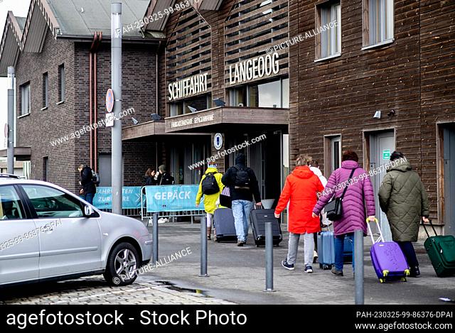 25 March 2023, Lower Saxony, Bensersiel: Tourists go with their luggage to the ferry terminal in the port to take a ferry to the island of Langeoog