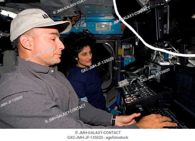 Astronauts Lee Archambault (foreground) and Sunita L. Williams, STS-117 pilot and mission specialist, respectively, work the controls of the Space Station...