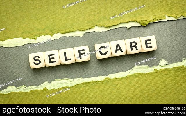self care word abstract in wooden cube letters on a handmade paper - mental, emotional, and physical health concept