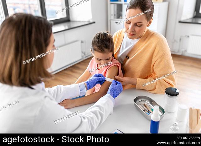 doctor sticking patch to child's arm at clinic