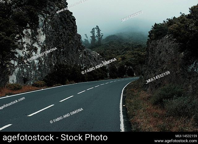 Destination and travel on the road concept. Long ashpalt straight road with scenic mountains and forest around. Outdoors driving journey