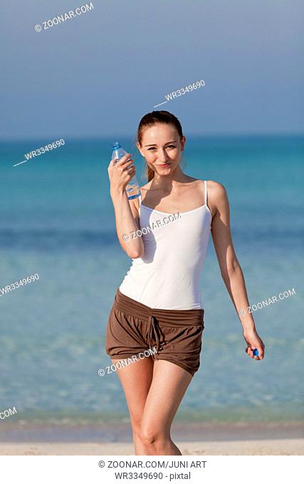Junge Frau mädchen trinkt erfrischendes Wasser aus einer Flasche am Strand am Meer im Sommer Urlaub