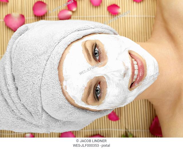 Young woman with face mask at spa, smiling, portrait