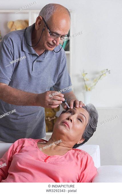 Old woman getting eye drops put in