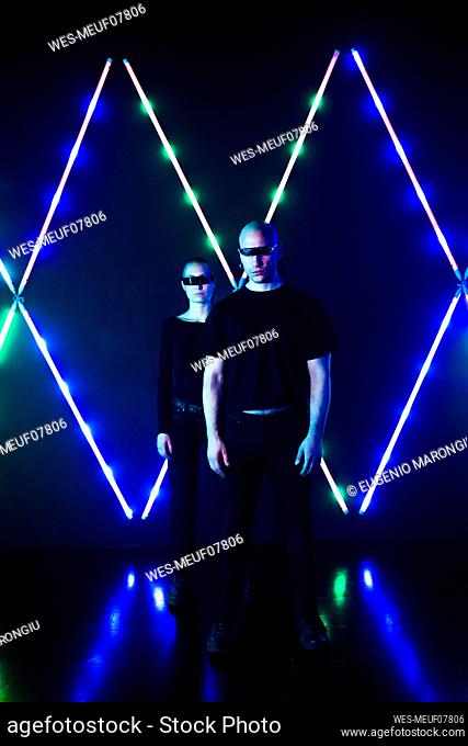 Couple wearing smart glasses standing in front of neon lights