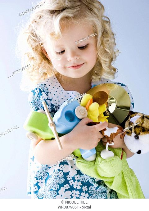 little girl holding an armful of her toys