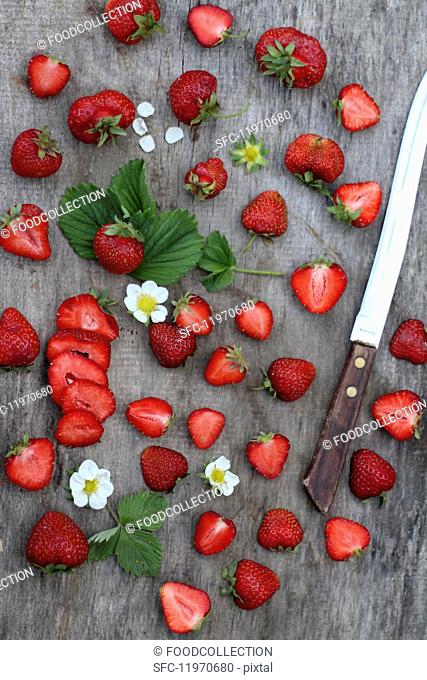 Fresh strawberries, whole and halved, on a wooden surface