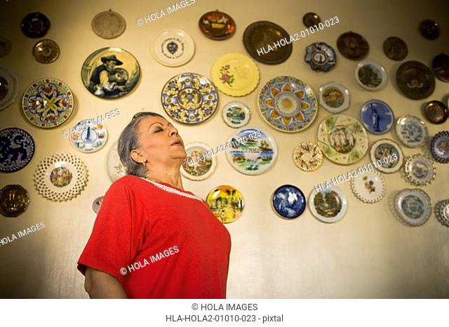 Mature woman near wall decorated with ceramics