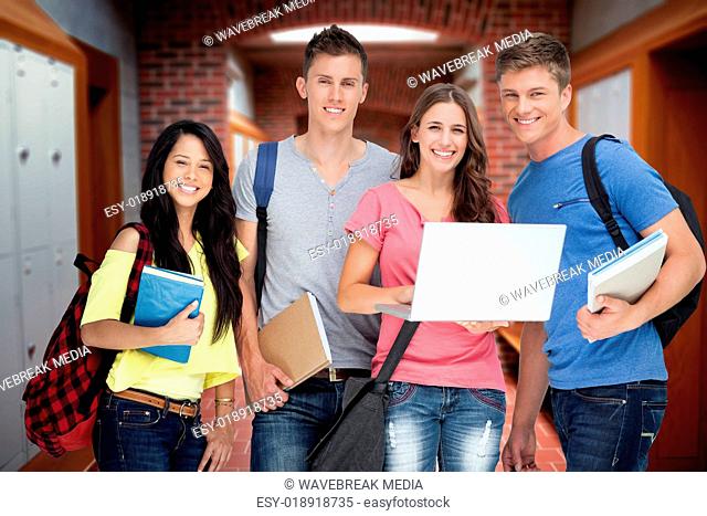 Composite image of a smiling group of students holding a laptop while looking at the camera