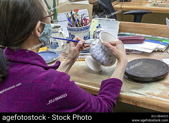 Holland, Michigan - An artist paints Delftware at the De Klomp Wooden Shoe and Delft Factory, part of the Veldheer Tulip Farm