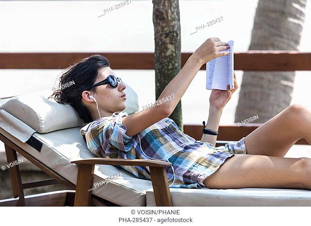 Teanage girl reading a book and listening to music