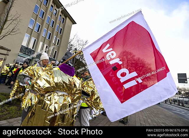 15 March 2023, North Rhine-Westphalia, Gelsenkirchen: A flag of the Ver.di union at the demonstration in Gelsenkirchen, the strikers in golden capes