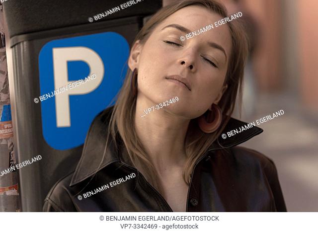 stressed woman resting on parking meter