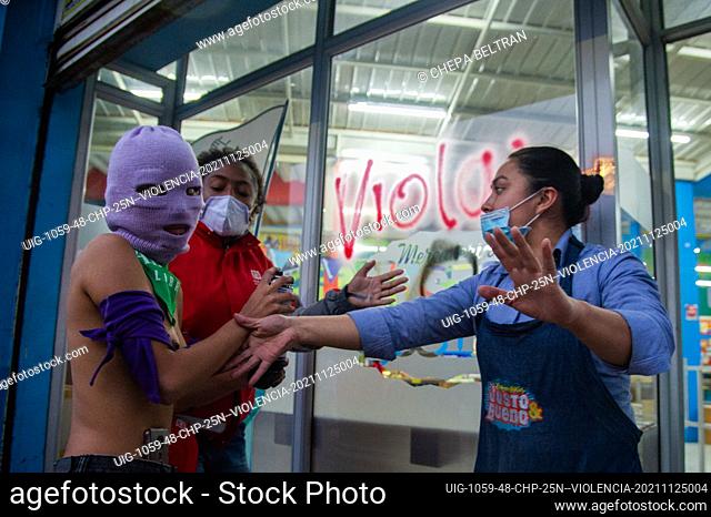 A radical feminist is held back after graffiting a supermarket window during the International Day for the Elimination of Violence against Women demonstrations...