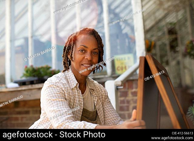 Portrait confident female plant nursery owner with signboard