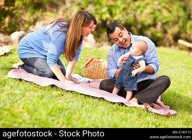 Happy mixed-race family having a picnic and playing in the park