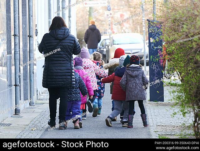 16 March 2020, Berlin: Some children walk on the pavement with a chaperone. The kindergartens and day-care centres are closing this week because of the Corona...