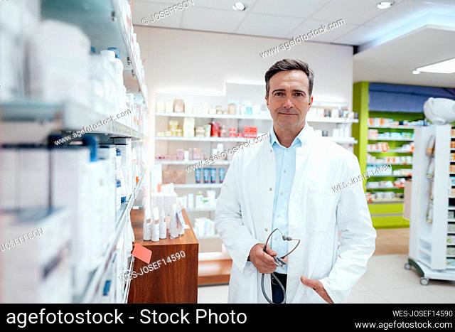 Man in lab coat holding stethoscope in pharmacy