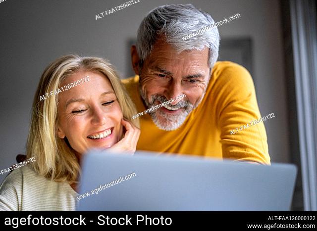 Smiling mature couple using laptop