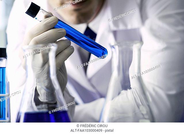 Chemist examining test tube containing blue liquid, cropped