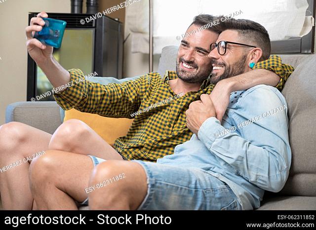 Young smiling gay couple taking selfie at home. High quality photography