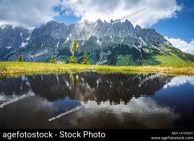 mountain pond with wilder kaiser range reflecting in water pond, tirol - austria