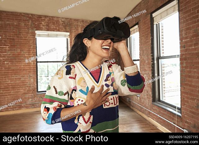 portrait of young ethnic woman wearing VR headset in empty loft
