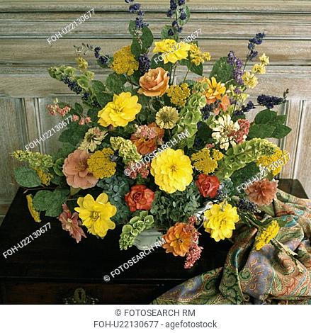 Yellow dahlias and green molucella in formal flower arrangement with orange roses and dahlias