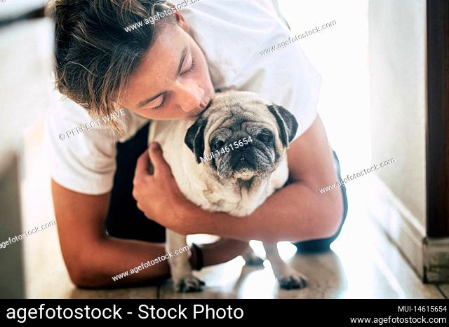 couple of teenager and cute white pug - love and affection of two best frieds at home - loving the animals