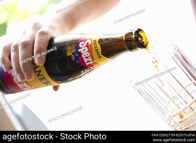 ILLUSTRATION - 27 June 2022, Bavaria, Munich: A young woman pours Spezi into a glass for an illustration. Photo: Lennart Preiss/dpa