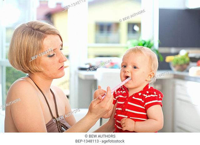 Mother dosing up her baby with a syrup