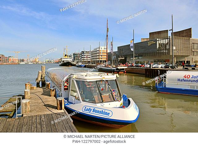Bremerhaven's new harbour with wooden boatbridge and the excursion boat Lady Sunshine and the museum Deutsches Auswandererhaus at the right bank