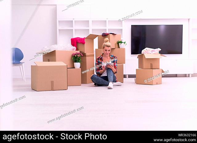 people, moving new place and repair concept  happy beautiful young woman with many cardboard boxes sitting on floor with Cup at home