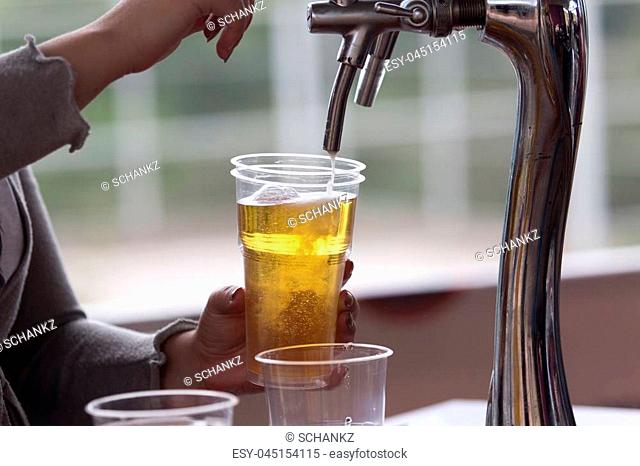 Barman pours beer into a plastic glass