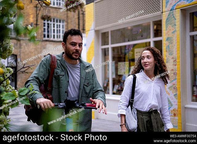Man walking with girlfriend in front of building on footpath