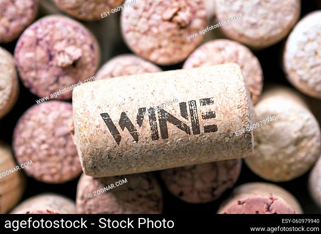 single wine cork with wine word print laying on the many corks background
