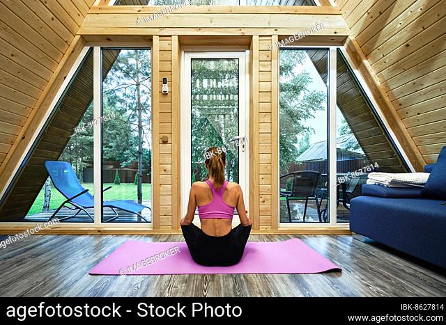 Woman practicing yoga lotus position in forest house