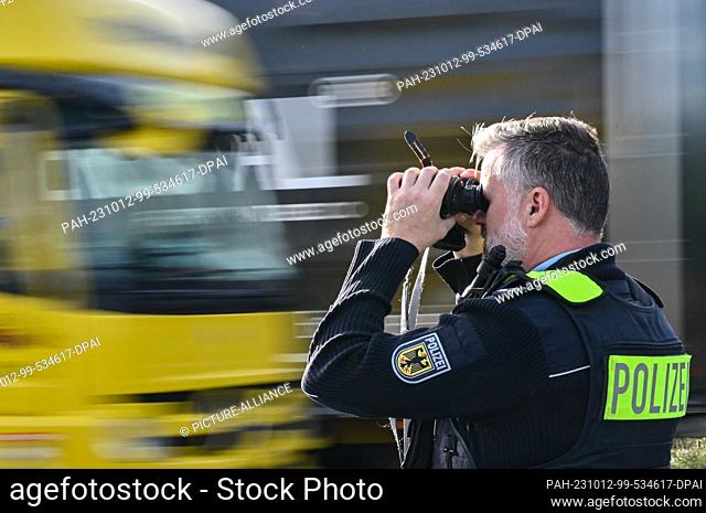 11 October 2023, Brandenburg, Forst: A federal police officer observes traffic through binoculars on the A15 highway from Poland to Germany near the state...