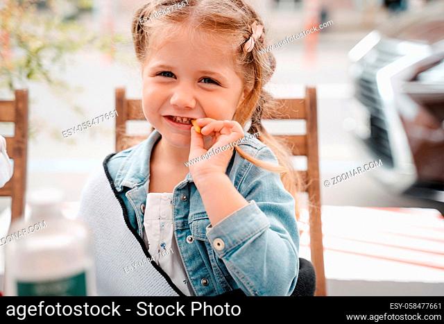 Little girl in a street cafe with french fries