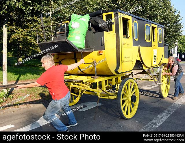 14 September 2021, Saxony, Leipzig: Coachman Siegfried Händler (r) drives his historic stagecoach with his sister Kerstin Händler to hitch up the horses at the...