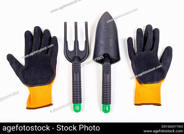 Work gloves, rake and spatula. Accessories for people working in the garden. Light background