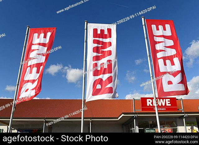 25 February 2020, Hessen, Volkmarsen: Flags with the logo of the food retailer Rewe are waving in front of a branch. Photo: Uwe Zucchi/dpa