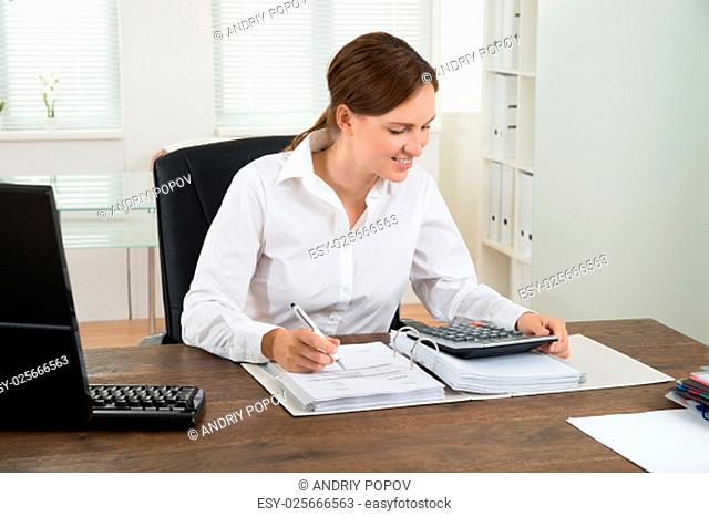 Photo Of Happy Businesswoman Calculating Invoice At Desk