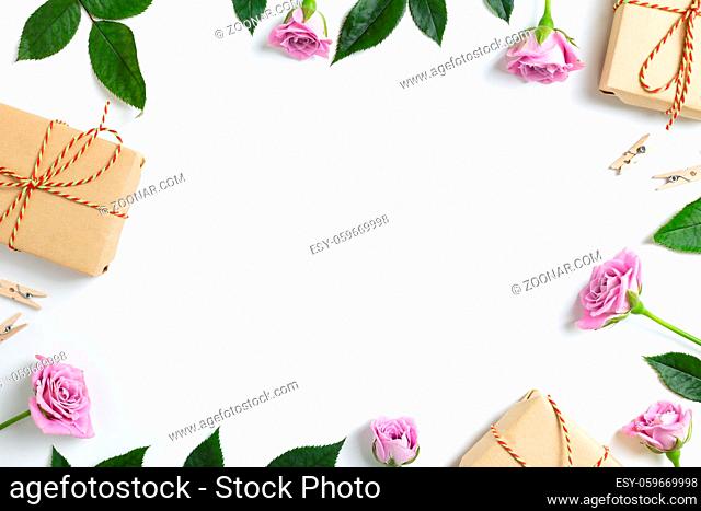Pink rose flowers with gift boxes on white background. Floral composition, flat lay, top view, copy space
