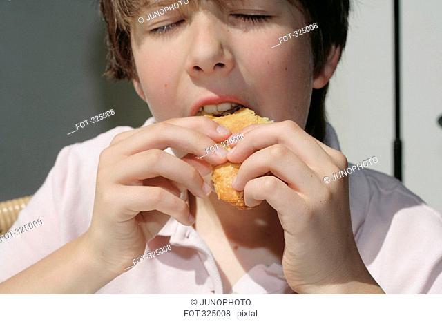 Boy eating bread roll