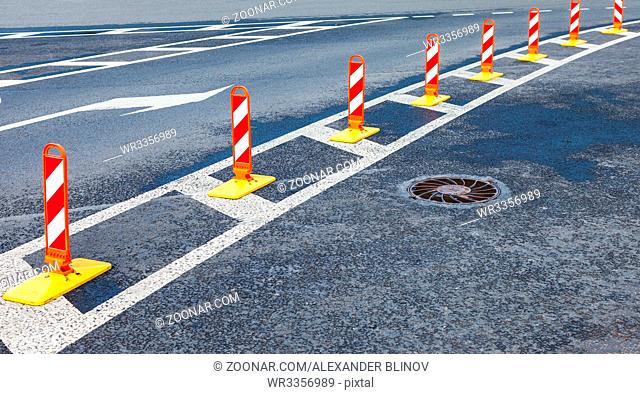 St. Petersburg, Russia - July 31, 2017: Traffic safety. Traffic markings on a gray asphalt. Red and white striped caution road sign
