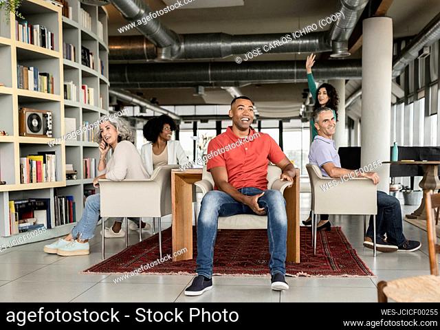 Happy colleagues sitting on chairs at office