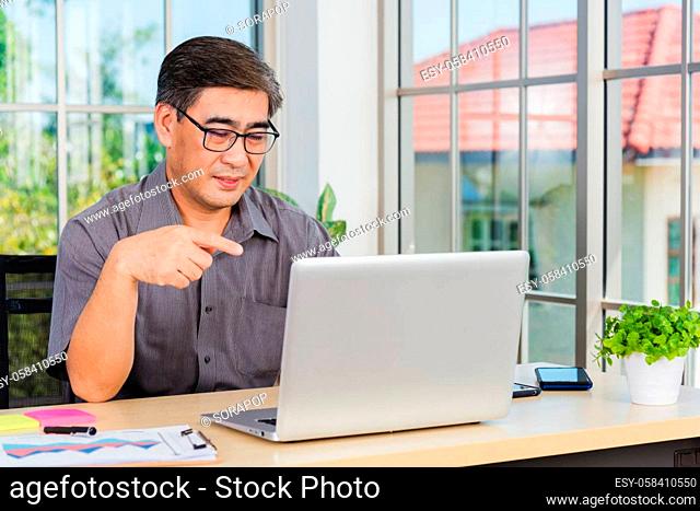 Asian senior business man working online on a modern laptop computer he looking at the screen for remote online studying