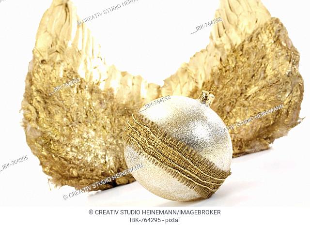 Gold ribbon wrapped around a Christmas ornament in front of golden angel wings
