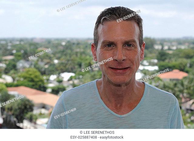 Good looking caucasian male in is forties with a nice smile outside on a tenth floor balcony showing a high view of residential and commercial areas of Fort...